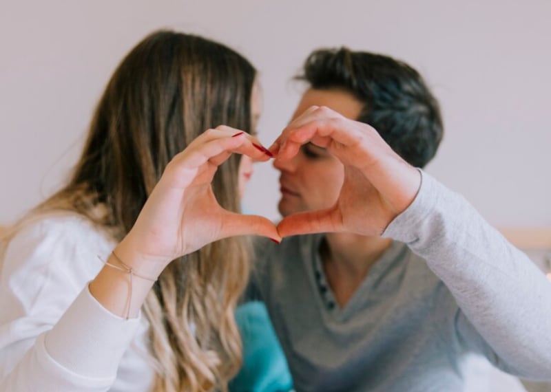 Pareja mostrando el gesto del corazón antes de besar.