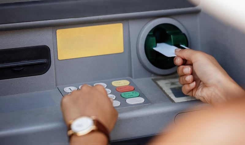 Primer plano de una mujer escribiendo el código PIN mientras retira dinero del cajero automático.