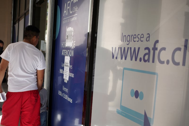 Personas esperando a las afueras de la sucursal de la AFC de la comuna de Santiago, ubicada entre las calles Agustinas y Teatinos, para cobrar su seguro de cesantía.