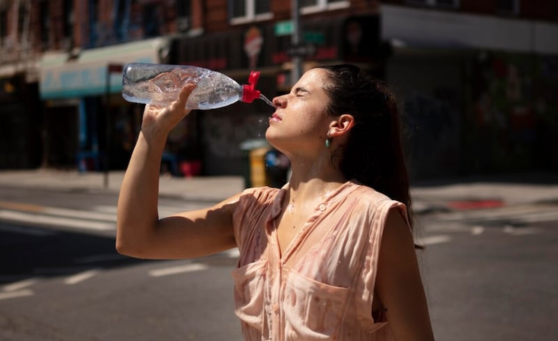 Mujer joven tolerando la ola de calor con una bebida fría